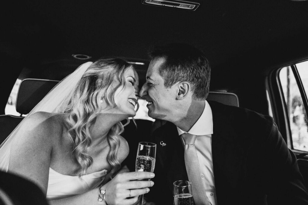 Bride and groom celebrating inside a luxury limousine, toasting with champagne on their wedding day in Vail, Colorado